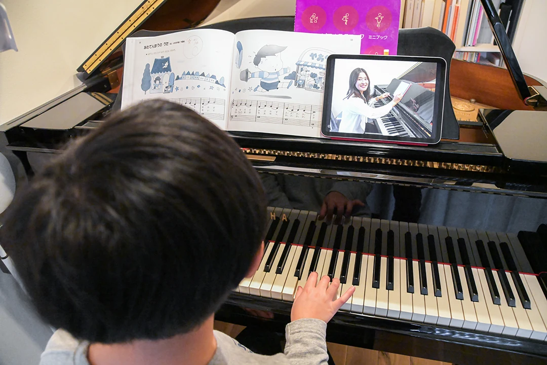 A child taking an online trial lesson on their piano at home.